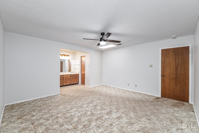 unfurnished bedroom featuring ceiling fan, visible vents, light colored carpet, baseboards, and ensuite bathroom