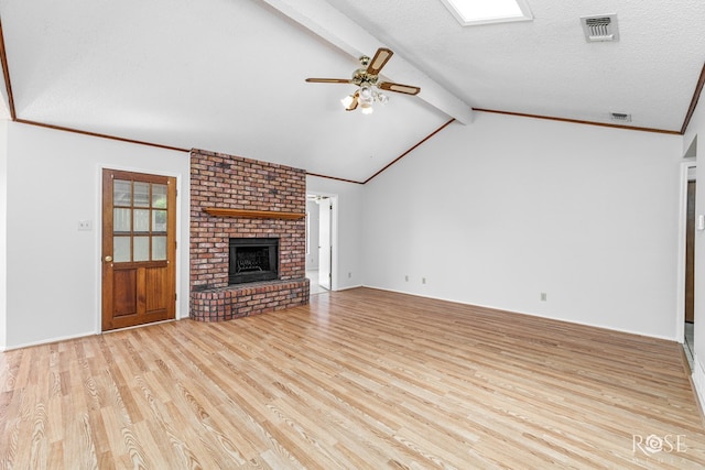 unfurnished living room with a brick fireplace, a ceiling fan, wood finished floors, and visible vents