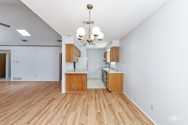 kitchen featuring freestanding refrigerator, brown cabinets, and visible vents