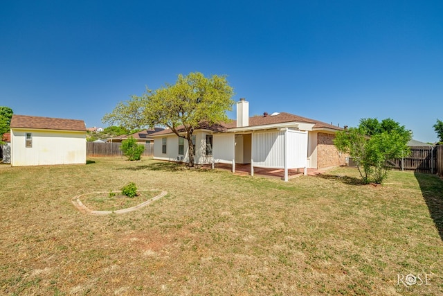 back of house with a fenced backyard, a chimney, and a yard
