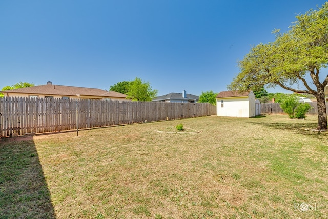 view of yard featuring a storage unit, a fenced backyard, and an outbuilding