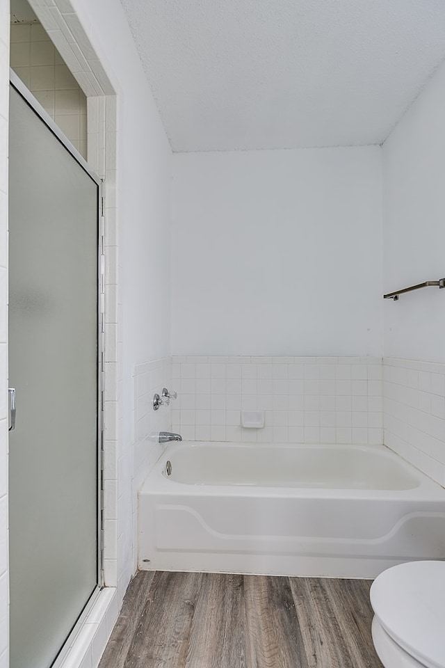 bathroom featuring hardwood / wood-style flooring, shower with separate bathtub, a textured ceiling, and toilet