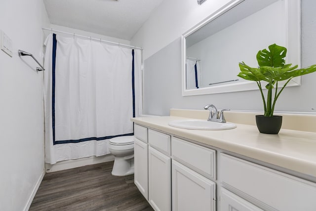 bathroom featuring curtained shower, wood-type flooring, vanity, toilet, and a textured ceiling