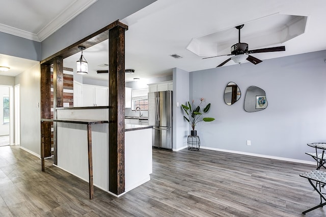 kitchen featuring a kitchen bar, white cabinetry, dark hardwood / wood-style flooring, stainless steel fridge, and kitchen peninsula