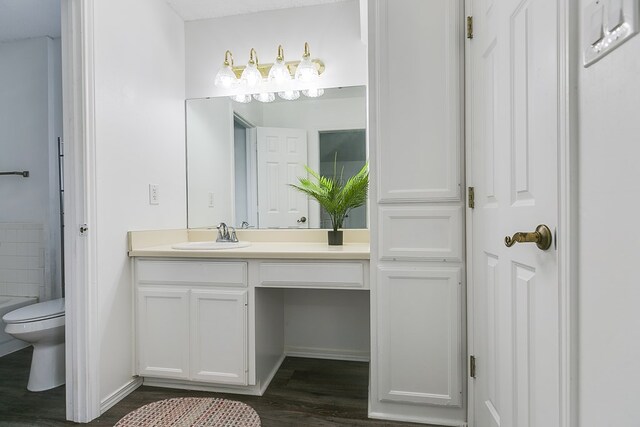 bathroom with hardwood / wood-style flooring, vanity, toilet, and a bath