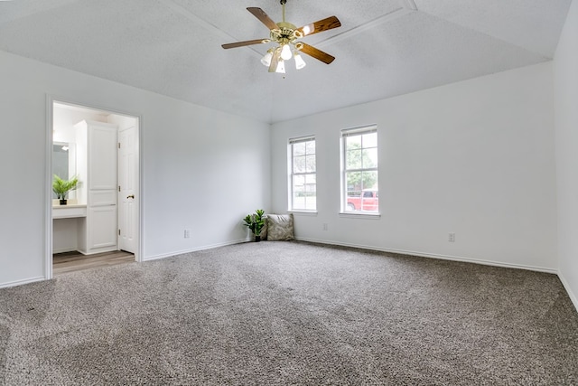 carpeted empty room with vaulted ceiling, a textured ceiling, and ceiling fan