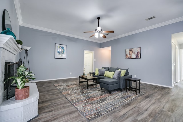 living room featuring ornamental molding, dark wood-type flooring, ceiling fan, and a fireplace