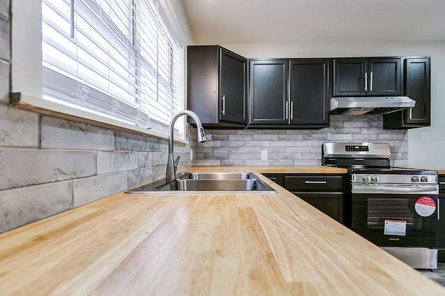 2729 Rio Grande St, San Angelo, TX 76904 - kitchen with butcher block countertops, stainless steel electric range oven, under cabinet range hood, a sink, and dark cabinets