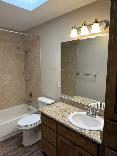 full bathroom with wood finished floors, a skylight, vanity,  shower combination, and toilet