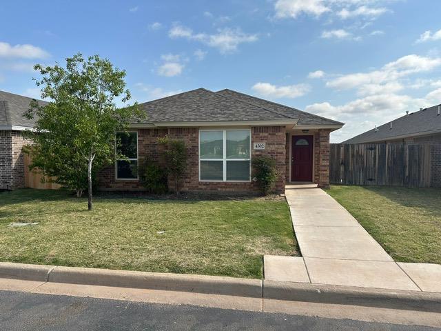 ranch-style home featuring brick siding, a front lawn, and fence