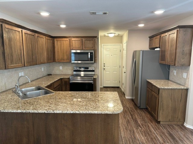 kitchen with tasteful backsplash, a sink, appliances with stainless steel finishes, dark wood-type flooring, and visible vents