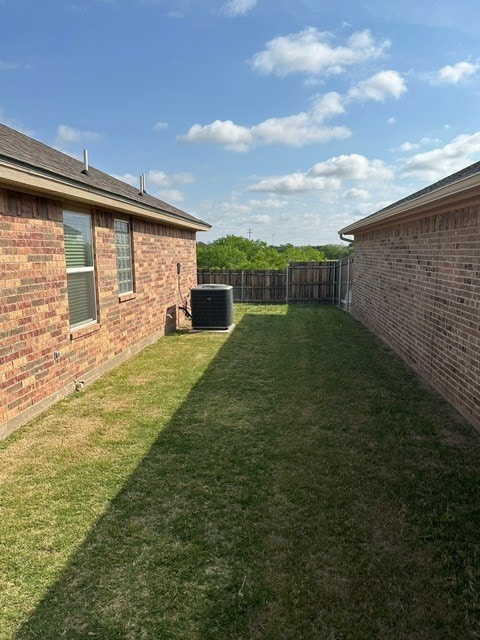 view of yard with fence and central AC unit
