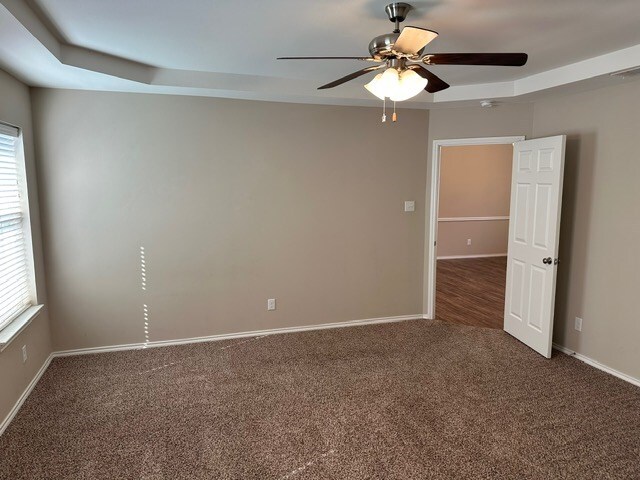 carpeted spare room featuring ceiling fan and baseboards