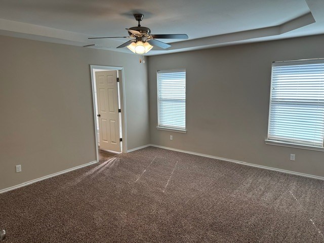carpeted empty room with baseboards and a ceiling fan