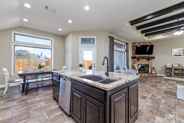 5922 Tarin St, San Angelo, TX 76904 - kitchen with dishwasher, a stone fireplace, open floor plan, dark brown cabinets, and a center island with sink