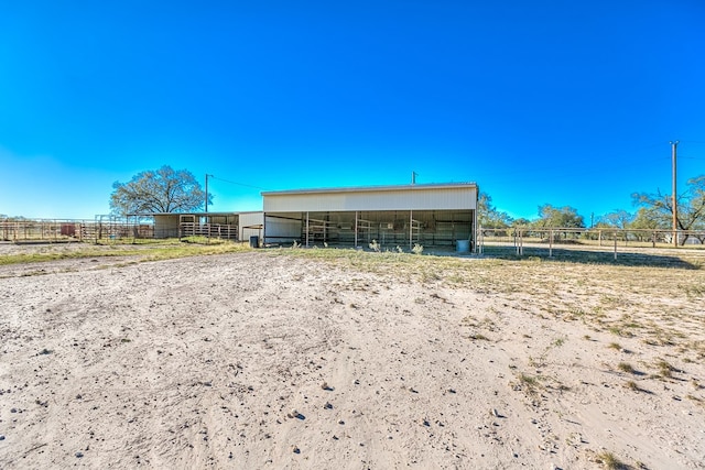 rear view of property with a rural view and an outdoor structure