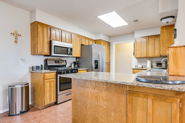 kitchen featuring light tile patterned floors, light stone countertops, kitchen peninsula, and appliances with stainless steel finishes