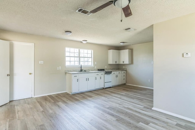 kitchen with sink, white cabinetry, white range oven, a textured ceiling, and light wood-type flooring