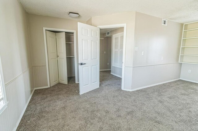 unfurnished bedroom featuring a closet, carpet flooring, and a textured ceiling