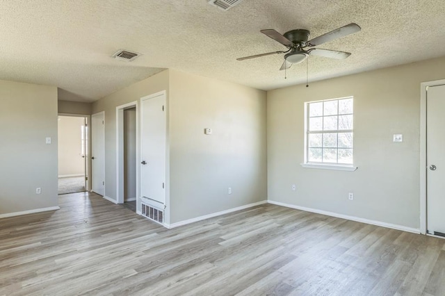 unfurnished room with ceiling fan, a textured ceiling, and light wood-type flooring