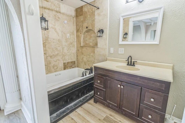 bathroom with wood-type flooring, tiled shower / bath combo, and vanity