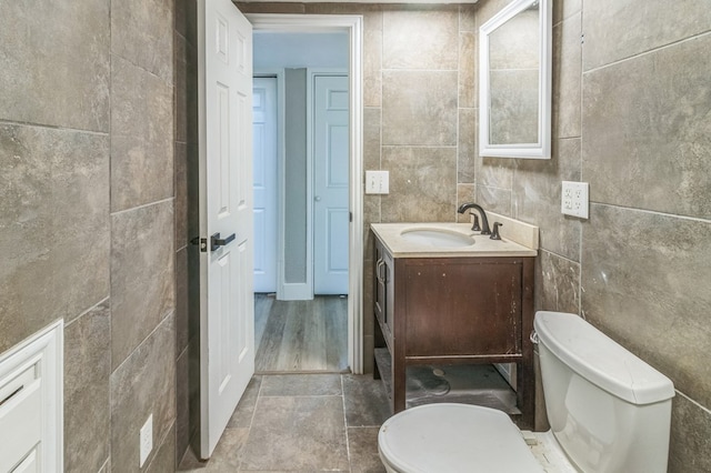 bathroom featuring vanity, toilet, and tile walls