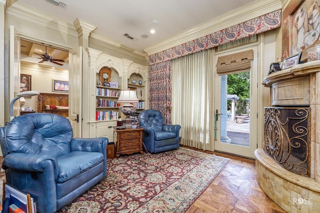 sitting room with ornamental molding, parquet floors, built in features, and ceiling fan