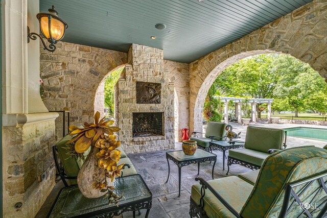 view of patio with an outdoor stone fireplace and a pergola