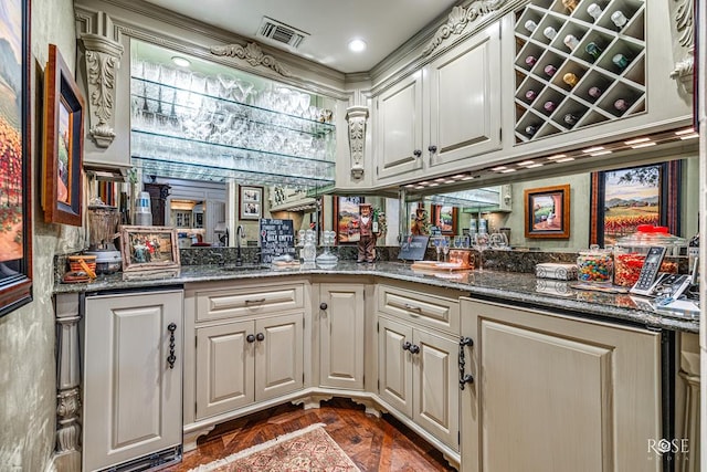 bar with dark stone countertops, sink, and white cabinetry