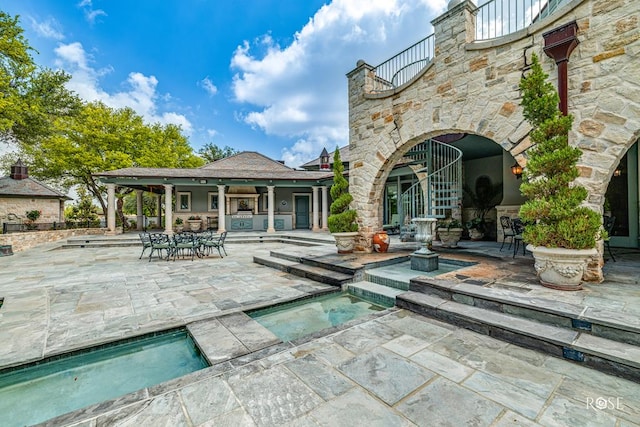 exterior space featuring a balcony and a pool with hot tub