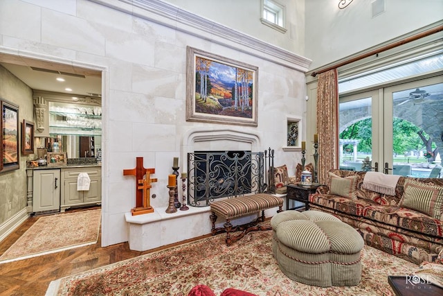 living room with french doors, parquet flooring, tile walls, a fireplace, and a high ceiling