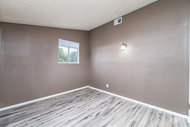 empty room featuring a textured ceiling and light hardwood / wood-style floors