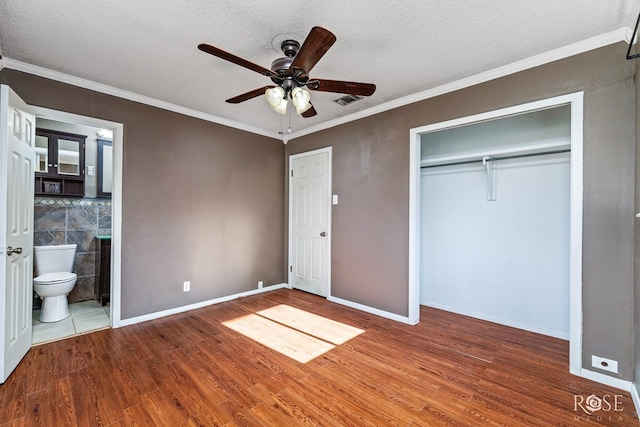 unfurnished bedroom with crown molding, hardwood / wood-style floors, ceiling fan, and a closet