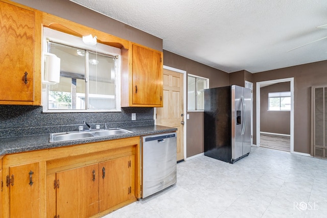 kitchen featuring stainless steel appliances, sink, a textured ceiling, and decorative backsplash