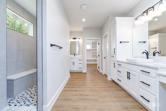 2734 Oak Hills Trl, San Angelo, TX 76904 - bathroom featuring two vanities, wood finished floors, walk in shower, recessed lighting, and baseboards