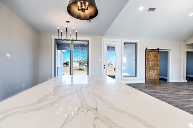 unfurnished room with dark hardwood / wood-style flooring, a notable chandelier, and a barn door