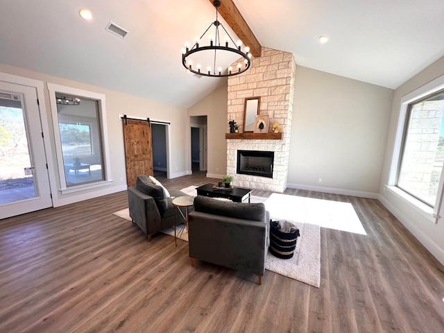 living room featuring vaulted ceiling with beams, a barn door, plenty of natural light, dark hardwood / wood-style floors, and a fireplace