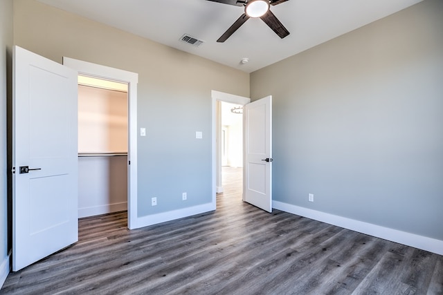 unfurnished bedroom featuring dark hardwood / wood-style flooring, a spacious closet, ceiling fan, and a closet