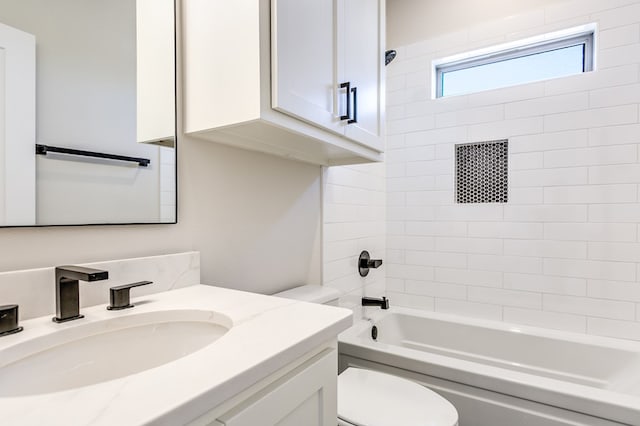 full bathroom featuring vanity, tiled shower / bath combo, and toilet