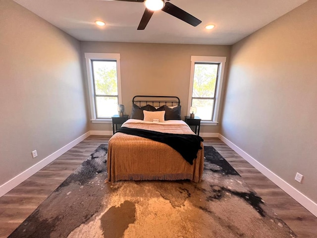 bedroom with multiple windows, wood-type flooring, and ceiling fan