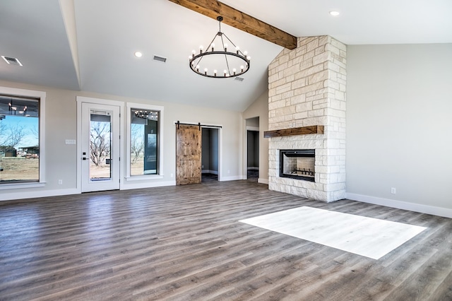 unfurnished living room with a barn door, vaulted ceiling with beams, and dark hardwood / wood-style floors