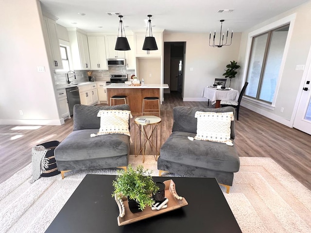 living room featuring wood-type flooring, a chandelier, and sink