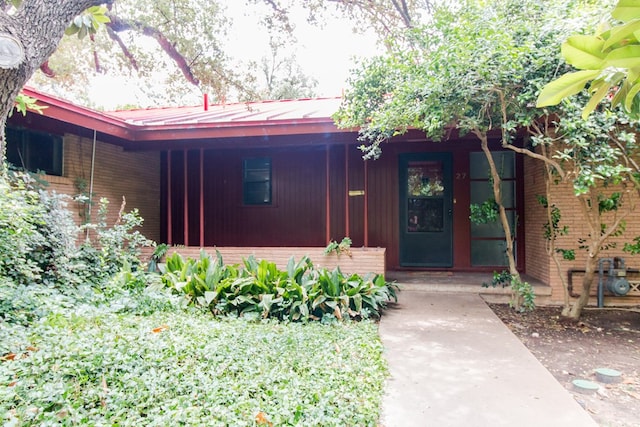 27 Yucca St, San Angelo, TX 76901 - entrance to property featuring brick siding, covered porch, and metal roof