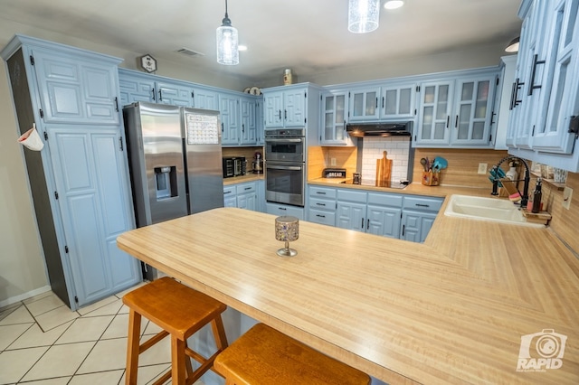 3709 Tridens Trl, San Angelo, TX 76904 - kitchen featuring appliances with stainless steel finishes, a peninsula, light countertops, glass insert cabinets, and under cabinet range hood