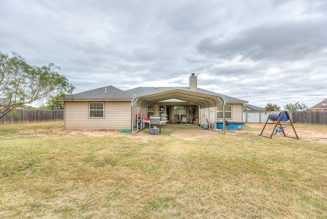 rear view of house featuring a carport and a yard