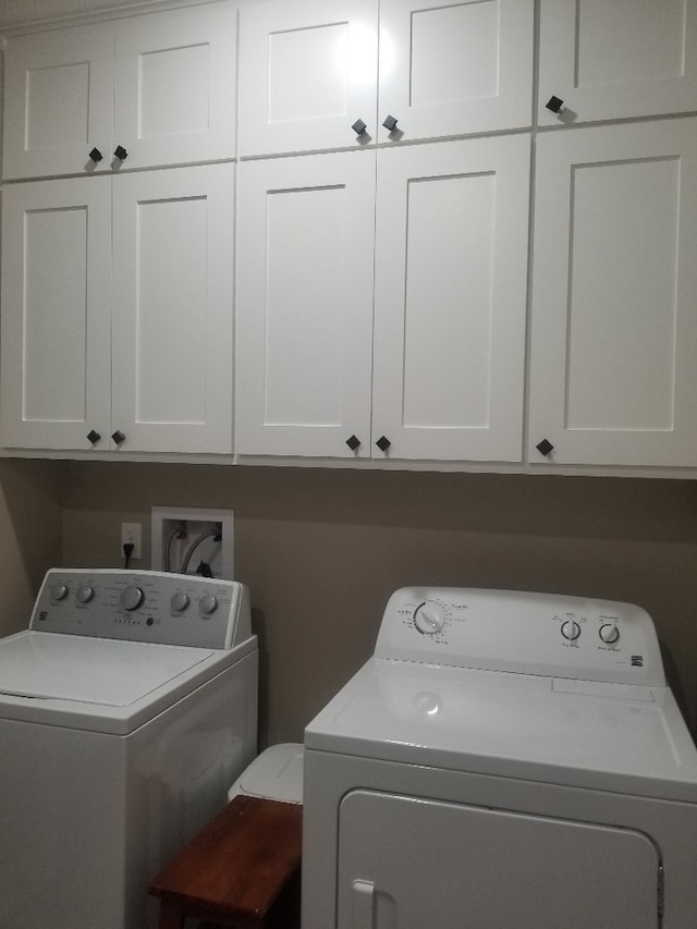 washroom featuring cabinets and washer and clothes dryer