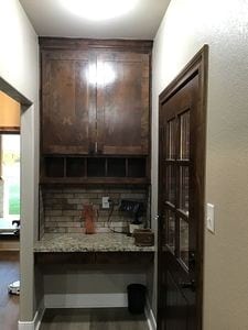 bar with dark brown cabinets and light stone counters