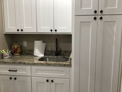 bar featuring light stone counters, sink, and white cabinets