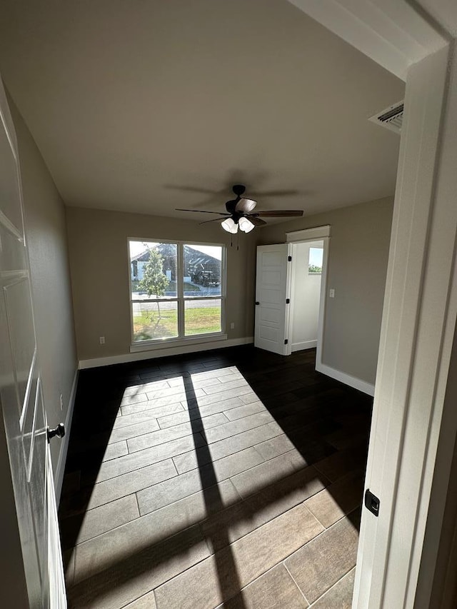5610 Slayde St, San Angelo, TX 76904 - empty room featuring baseboards, a ceiling fan, and dark wood finished floors