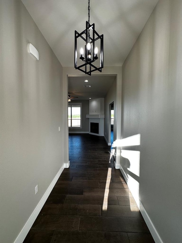 5610 Slayde St, San Angelo, TX 76904 - hall featuring a chandelier, baseboards, and dark wood-style flooring